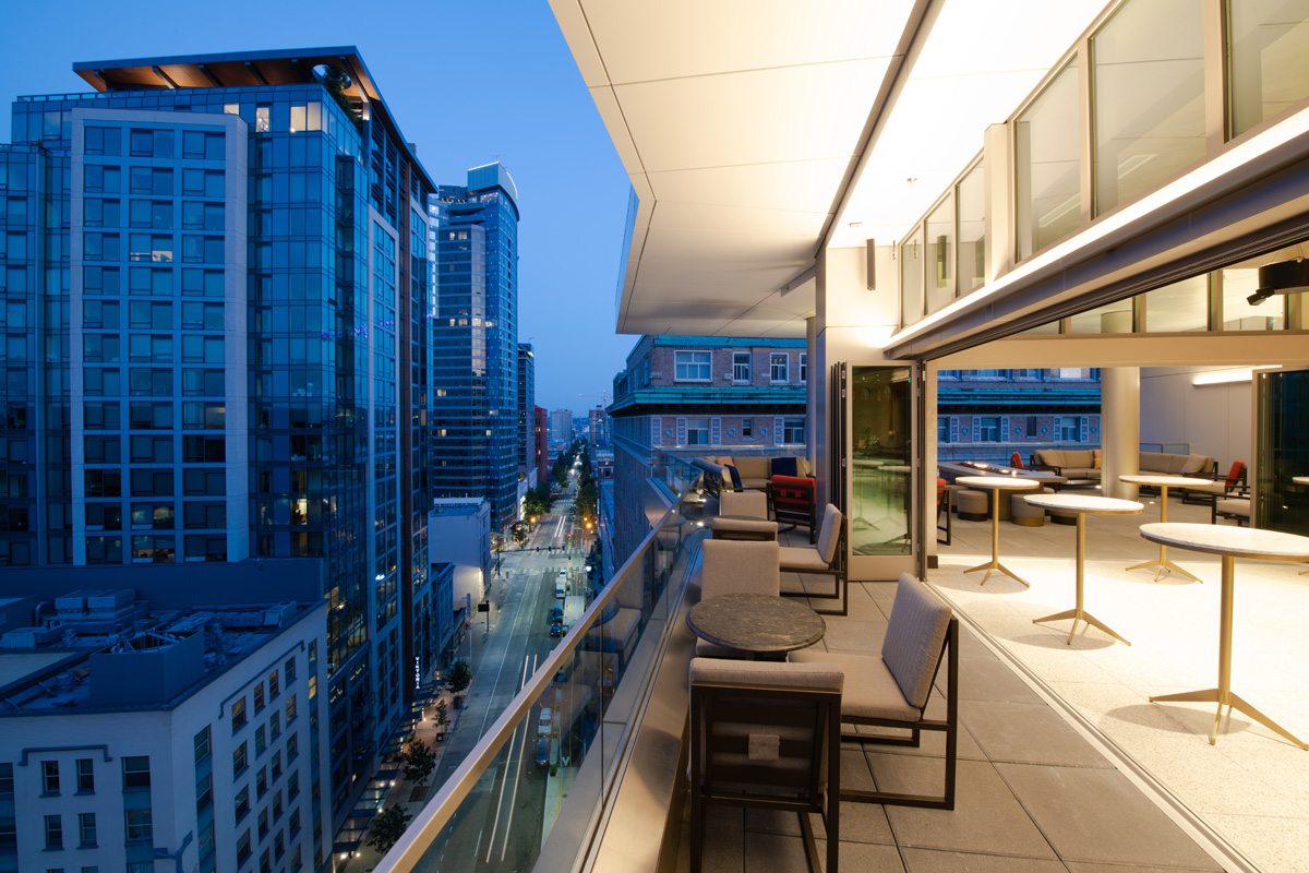 A balcony with furniture and a city view at evening